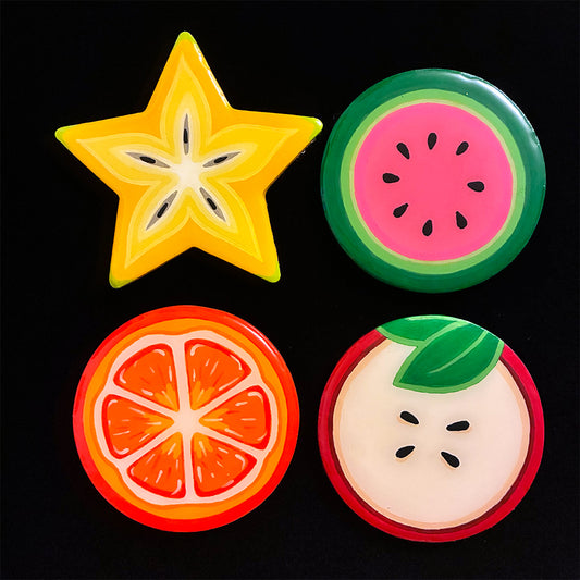 Four colorful fruits-themed coasters on a black background.