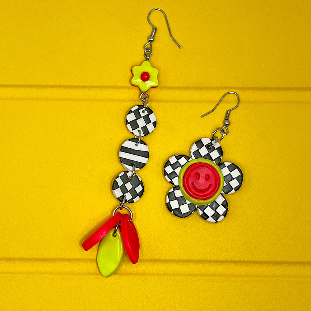 Lee's Art Studio smiley face checkered flower asymmetric pair of polymer clay earrings with lineal pattern and neon color details.
