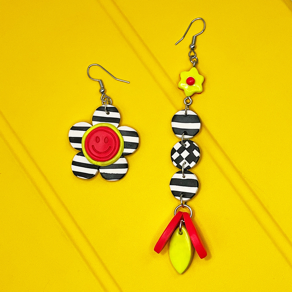 Lee's Art Studio smiley face lineal flower asymmetric pair of polymer clay earrings with checkered pattern and neon color details.