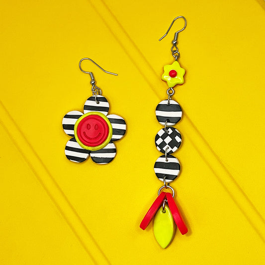 Lee's Art Studio smiley face lineal flower asymmetric pair of polymer clay earrings with checkered pattern and neon color details.