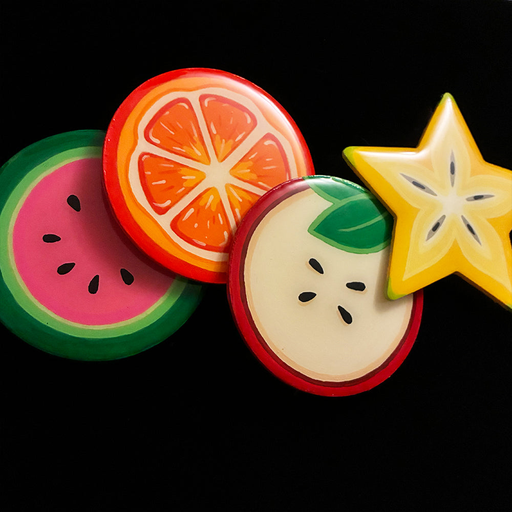 Fruit-themed coasters including watermelon, orange, apple, and star fruit on a black background.