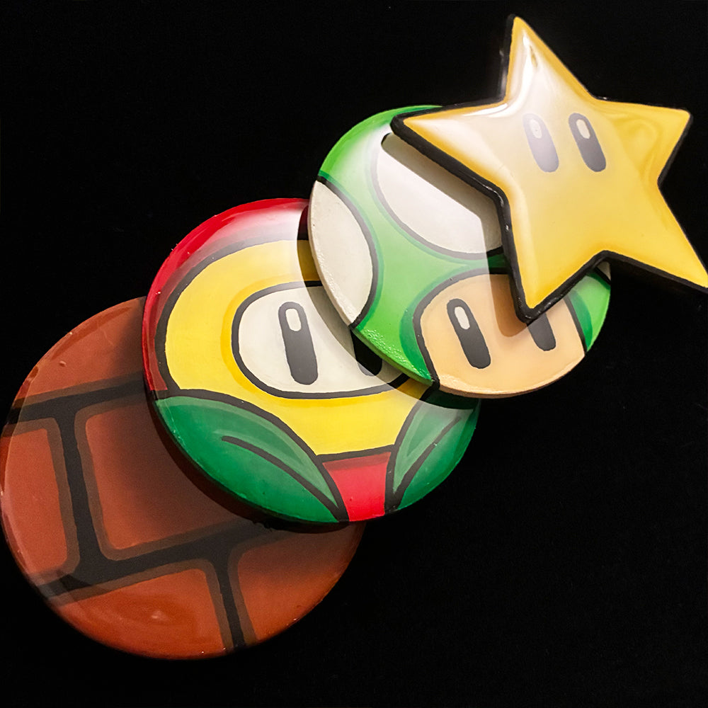 Four colorful coasters resembling characters from a video game on a black background