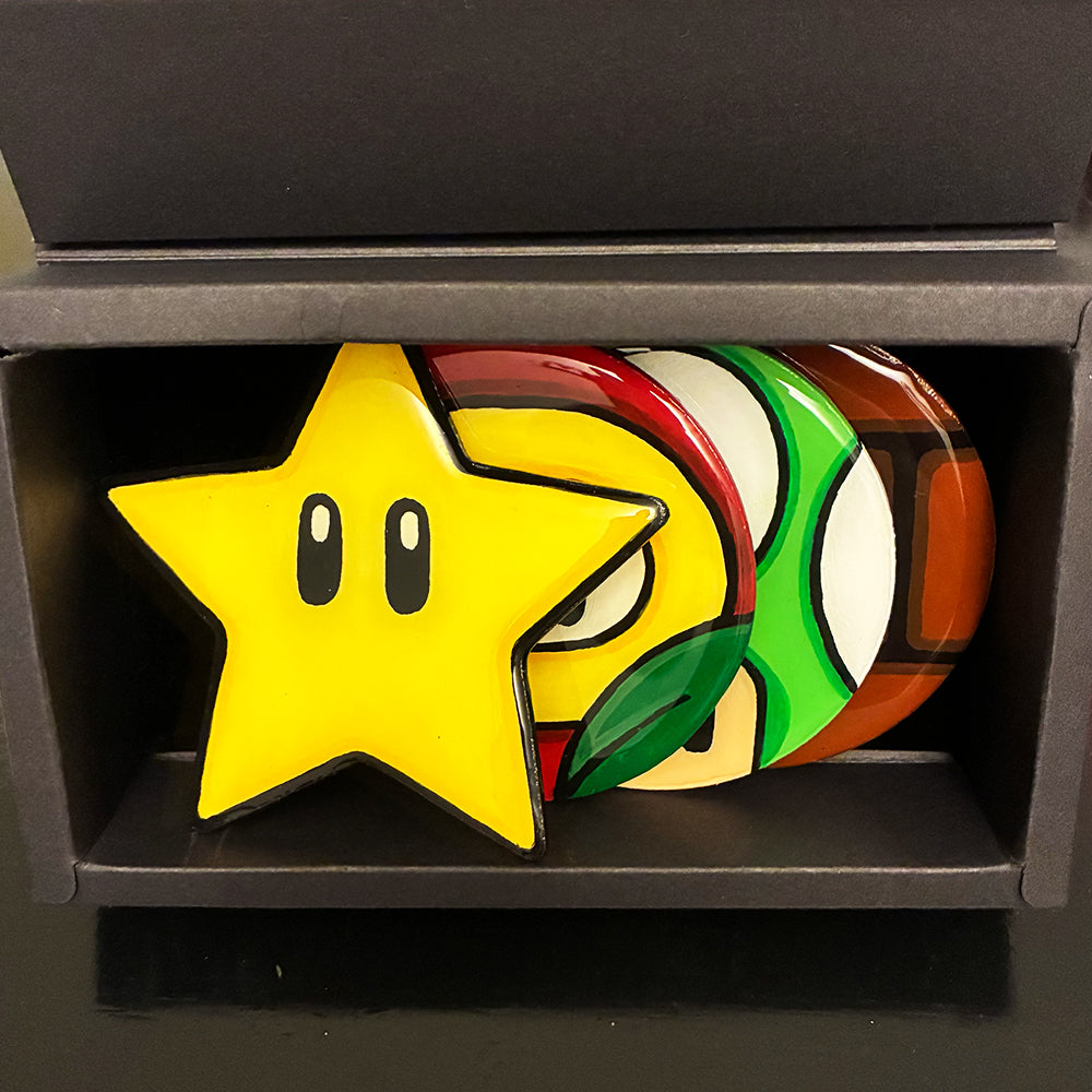 Colorful powwer-up coasters in a black display box